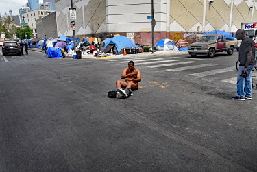 A homeless man sits naked in the middle of a road.  Thousands of homeless people camp out in the centre of Los Angeles, in an area of about 50 blocks. In greater Los Angeles, there are 70,000 homeless...