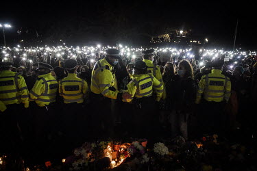 People hold up their smartphones in protest as police, citing COVID-19 lockdown regulations, move in to break up a vigil at the bandstand on Clapham Common held to demonstrate against male violence an...