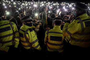 People hold up their smartphones in protest as police, citing COVID-19 lockdown regulations, move in to break up a vigil at the bandstand on Clapham Common held to demonstrate against male violence an...