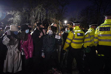 A woman holds up a sign demanding an end to violence again women, as police, citing COVID-19 lockdown regulations, begin to arrest people after attempting to break up a vigil at the bandstand on Claph...