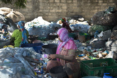 A woman sorting plastic by colour at a recycling business.