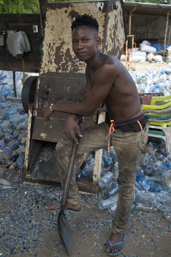 A man working at a plastic recycling business whose job is to load plastic bottles into the chipper machine.
