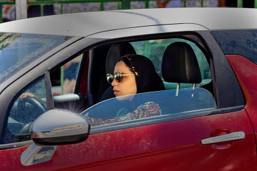 A young Muslim woman drives a car in the city centre.