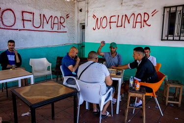 A group of men in a cafe, where 'No Smoking' is written prominently on the walls, in Benzu, a mainly Muslim district in the Spanish exclave of Ceuta, play a board game called Parchis.
