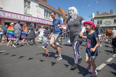 Holidaymakers join in with Morris dancers performing during the annual Sheringham Potty Morris festival.  Sheringham is a Victorian-era English seaside resort that was popular up through the 1950s bef...