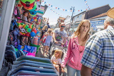 Tourists and locals walking past shops selling beach toys.  Sheringham is a Victorian-era English seaside resort that was popular up through the 1950s before mass travel to other parts of Europe becam...
