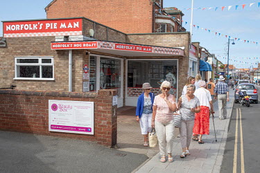 People walking past Norfolk's Pie Man, a take-away and restaurant in the town centre.  Sheringham is a Victorian-era English seaside resort that was popular up through the 1950s before mass travel to...