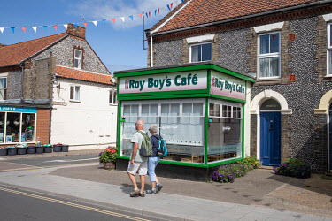 People walking past Roy Boy's Cafe, a restaurant in the town centre.  Sheringham is a Victorian-era English seaside resort that was popular up through the 1950s before mass travel to other parts of Eu...