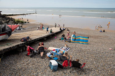Tourists relax on the town's shingle beach.  Sheringham is a Victorian-era English seaside resort that was popular up through the 1950s before mass travel to other parts of Europe became easily afford...
