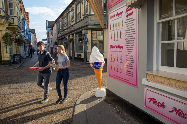 Tourists walk past an ice cream shop on the sea front.