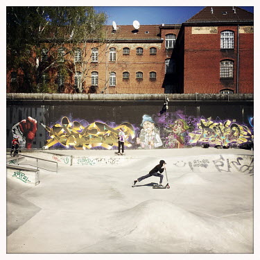 Skaters in front of a graffiti NW 21 and the prision Lehrter Strasse in Moabit. The Berlin district of Moabit is an artificial island completely surrounded by water that was once home to various indu...