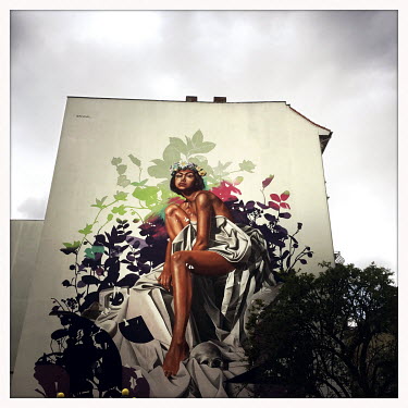 A mural of a woman on the wall of a building.  The Berlin district of Moabit is an artificial island completely surrounded by water that was once home to various industries and staunchly working-class...