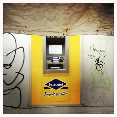 A cash point machine with the hoarding from a building site above.  The Berlin district of Moabit is an artificial island completely surrounded by water that was once home to various industries and st...