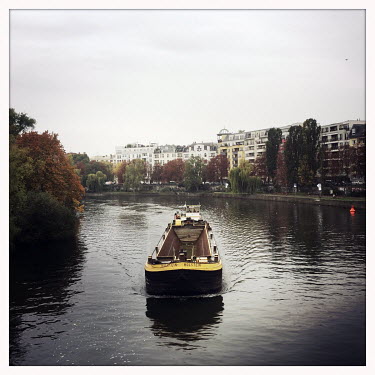 A barge on the river Spree.  The Berlin district of Moabit is an artificial island completely surrounded by water that was once home to various industries and staunchly working-class . However, with g...