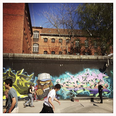 Skaters in front of a graffiti NW 21 and the prision Lehrter Strasse in Moabit.  The Berlin district of Moabit is an artificial island completely surrounded by water that was once home to various indu...