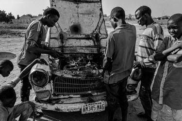 Men repair the engine of a 1968 Peugeot 404. Such vehicles are easy to maintain and an invaluable lifeline for those forced to risk their lives farming in the nearby countryside. The Borno State numbe...