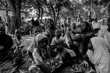 Several dozen people, almost all women and children, sheltering under a couple of large trees opposite the IDP camp's entrance, on the other side of the road. They were hungry and desperate and had be...