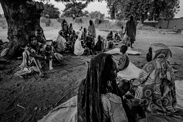 Several dozen people, almost all women and children, sheltering under a couple of large trees opposite the IDP camp's entrance, on the other side of the road. They were hungry and desperate and had be...