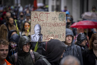 A man holds a placard featuring the image of Richard Attenborough at the 'opening ceremony' of the 'August 2021 Rebellion', a funeral march with an 'earth coffin' to The Guildhall, home to the City of...
