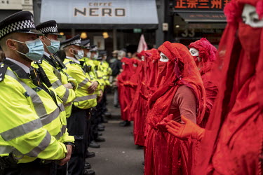 Extinction Rebellion activists The Red Brigade form a line in front of police during a march and occupation in London's West End.