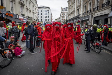 Extinction Rebellion activists The Red Brigade walk along St Martin's Lane during a march and occupation in London's West End.