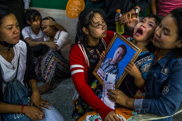 Shwe Yote Hlwar holds a portrait of her father as she weeps with her mother, Thet Htar, during the funeral of her father Zwe Htet Soe (26), a construction worker who was shot and killed when the milit...