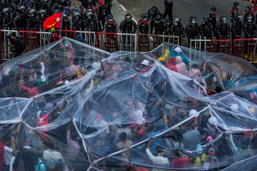 People use plastic sheeting to protect themselves from fire water canon used by the police as tens of thousands of people gather on University Avenue Road to protest against the military dictatorship,...