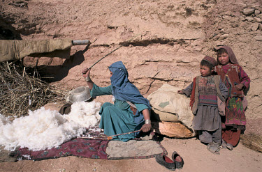 A Hazara woman prepares wool, usually sold in Kabul or made into quilts exchanged for food during the Afghan Civil War of 1992 - 1996.