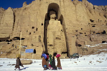 People walking past the large, or 'Western' Buddha of Bamiyan (55 metres high, 6th-7th century CE) in Bamiyan in the snow. The Buddhas were destroyed by the Taliban in 2001.
