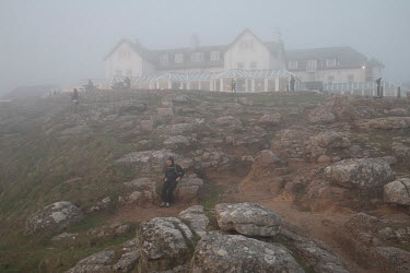 A heavy coastal mist envelopes tourists at Land's End, the westernmost spot on the British mainland with the Land's End hotel in the background.