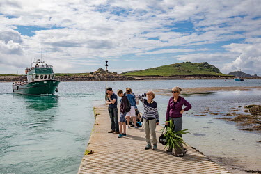 Cornwall, U.K. Tourists who missed an inter-island ferry on Tresco in the Scilly Isles, wait on the New Grimsby Quay for another boat. The Scillys, with their remote location off the southwestern tip...
