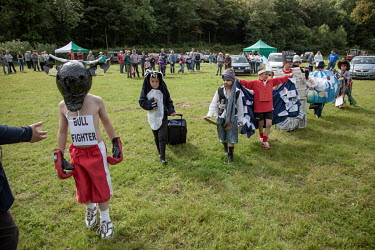 Children taking part in a costume contest at a village fete in North Pembrokeshire while their parents and spectators look on in the background.