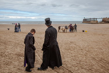 Participants in the semi-annual 'Goth Weekend' walk on the beach in Whitby. Goths, Victorian-era dressers, Steam-Punks and others flock to the town on the Yorkshire coast which is the setting in Bram...