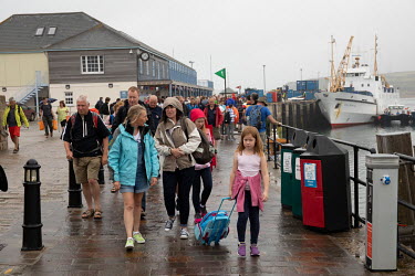 Tourists getting off the ferry from Penzance on a rainy day in Hugh Town, the main port on St. Mary's island in the Scilly Isles. The Scillys, with their remote location off the southwestern tip of Co...