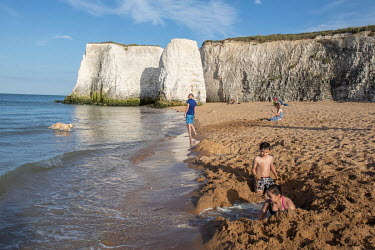 Children digging in the sand as the tide comes in on Broadstairs Beach in Kent.