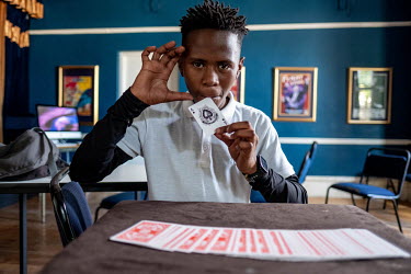 Duma Mgqoki, a student at the Cape Town College of Magic, practices a card trick in an empty classroom.
