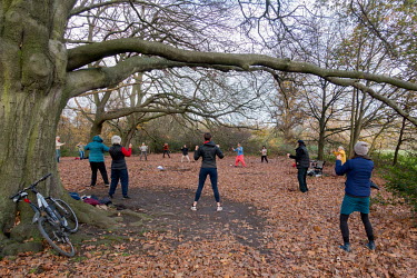 Outdoor meditation, exercise and spiritual well being class during Covid lockdown and social distancing restrictions on London's Hampstead Heath.