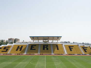 The small arena of the Sheriff sports complex with the name Sheriff spelled out in black letters on yellow seats. Sheriff is a private company that is involved in all sectors of business in the unreco...