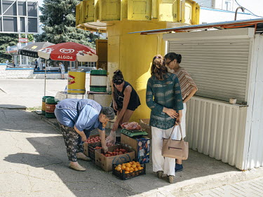 Women stand around a fruit vendor on a street corner in Tiraspol.
