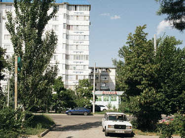 A high rise block in a residential area of Tiraspol with a pharmacy next to it.