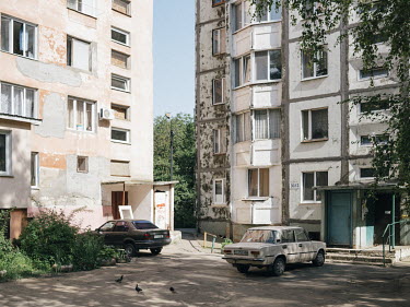 Cars parked in a courtyard surrounded by residential blocks in Tiraspol.