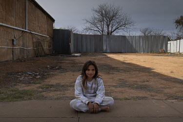 Hayley Dutton-Parke sits by herself in an empty lot next to the only shop in Wilcannia.