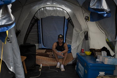 Allan Whyman, who is part of a 10 person household, sits inside a tent that the family has been given to help isolate covid positive members. The rest of the family are isolating in a small house next...