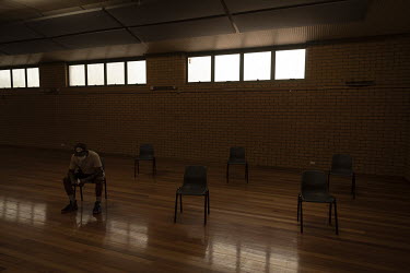 Anthony Elwood, 24, sits by himself in the main hall in Wilcannia, now serving as a waiting room, after being vaccinated.