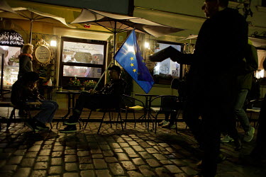 People attending a pro European Union ( EU ) rally sit on tables outside a restaurant. The rally was organised after a recent ruling by the country's Constitutional Court that Polish law stands above...
