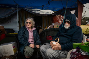 Jim and Ined Humphries drink coffee in front of their temporary home, a leaking caravan they have covered with a trampoline to protect them from the rain. Jim and Ined Humphries lost their home in a h...