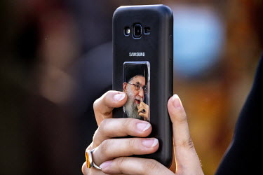 A woman takes a picture on a mobile phone, which is decorated with a picture of Ebrahim Raisi, during an election rally in Palestine Square for Raisi who was elected president of Iran in the vote held...