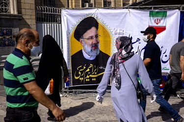 People walking past a banner displaying the image of Ebrahim Raisi who was elected president of Iran in a vote held on 18 June 2021.