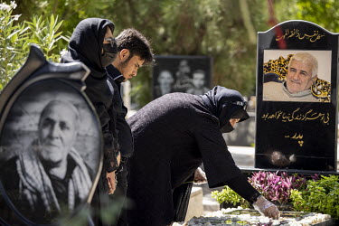 A family visits the grave of a relative in a cemetery for the martyrs of the Iran-Iraq war and also for the martyrs who died in Syria while fighting for the Bashar Hafez al-Assad regime.