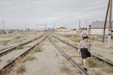 A young woman walks along rusty train tracks in the Aral Sea region of Kazakhstan.  The Aral Sea is one of over 48,000 lakes in Kazakhstan. It is almost dried up as a result of large-scale cultivation...